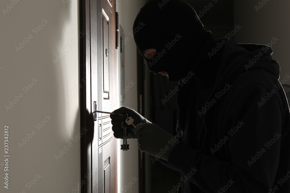 Male thief opening door with keys indoors Male thief opening door with keys indoors