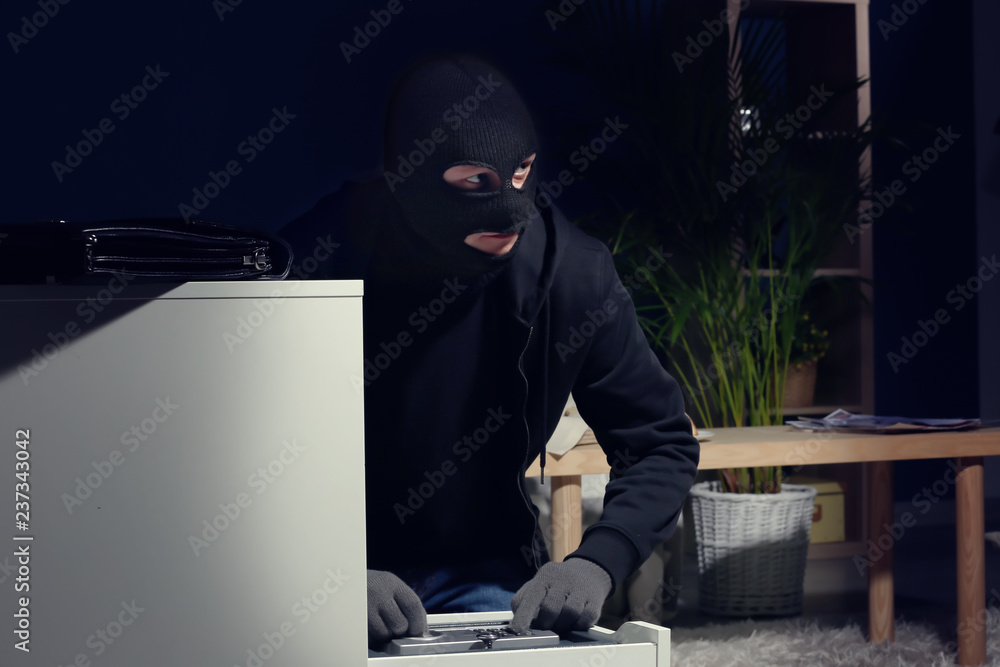 Male thief breaking safe indoors Male thief breaking safe indoors