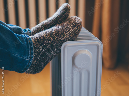 Feet in warm knitted socks on the heater. Heating season