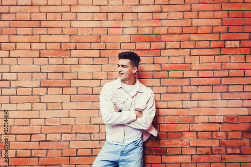 handsome young man posing against brick wall background