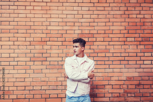 handsome man in a white jacket against a brick wall. copyspace