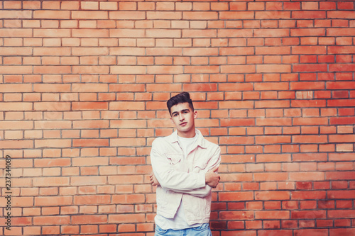 Stylish guy. Fashion man standing near brick wall