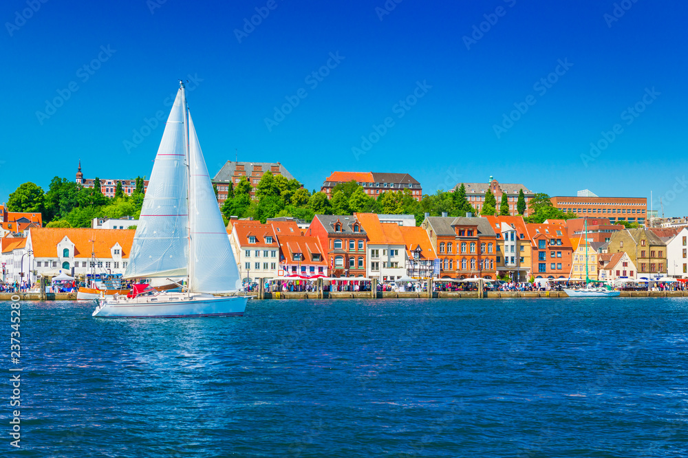 Beautiful panorama of a European port city. A yacht is sailing against the skyline of the city of Flensburg, Germany