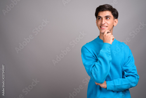 Young happy Persian teenage boy smiling and thinking