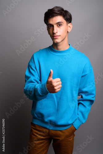 Young handsome Persian teenage boy giving thumb up