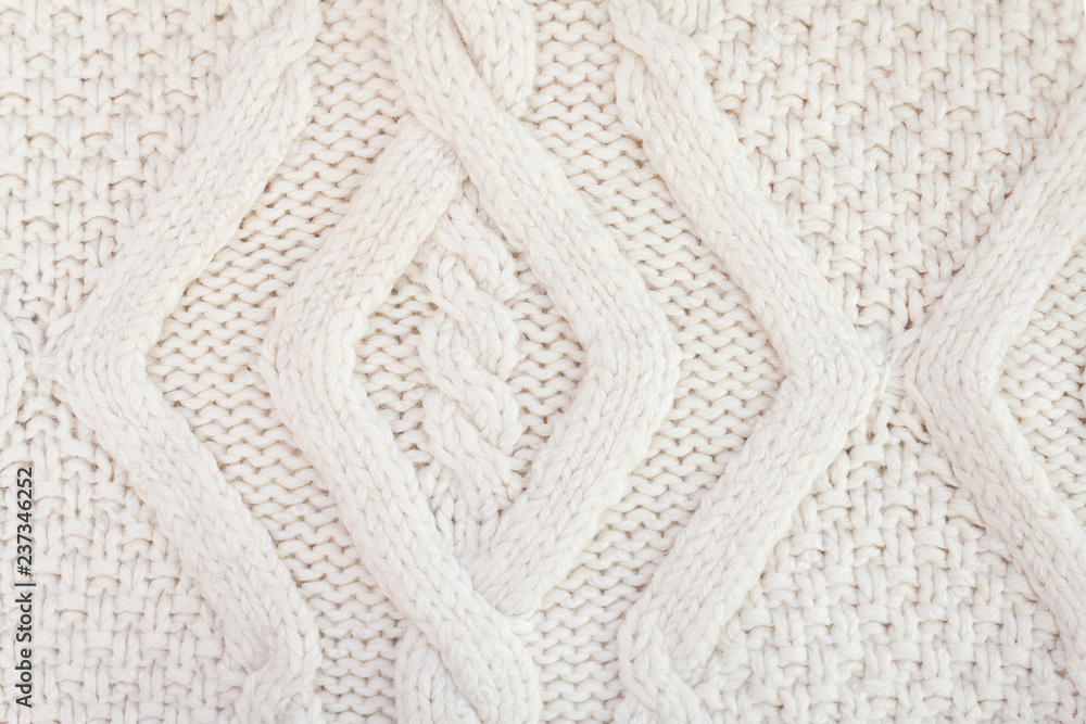 Knitted white fabric texture with a relief pattern. Warm winter clothes or blanket. Handmade texture