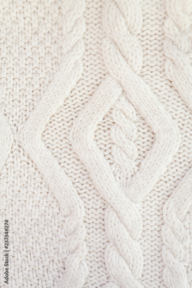 Knitted white fabric texture with a relief pattern. Warm winter clothes or blanket. Handmade texture