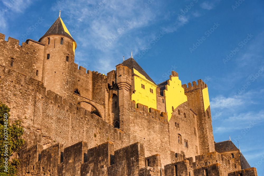 France, Carcassonne: Panorama front view of famous Cite de Carcassonne in the afternoon in the city center with high exterior wall, battlements and blue sky - concept travel history medieval castle