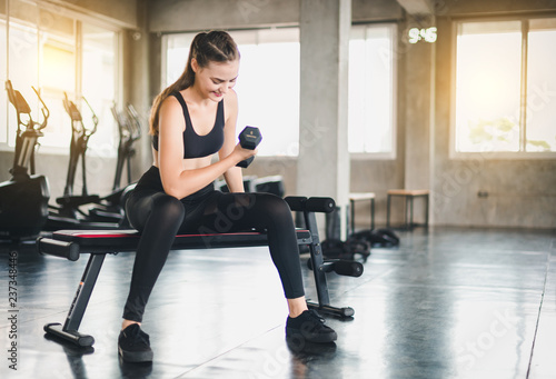 Beautiful girl caucasian is exercising with lifting dumbbell in the gym. Female athletes play a healthy training session.