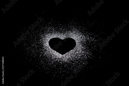 Heart shape made of icing sugar on total black background with copyspase. Concept of Valentine s day and sweet romantic love