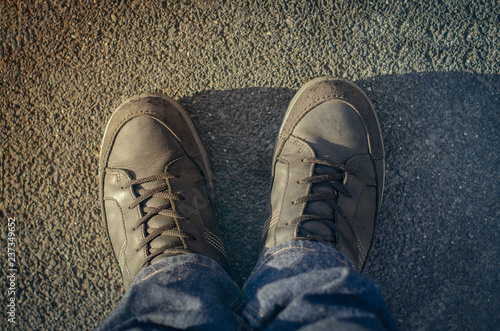 men's legs in black shoes on gray asphalt