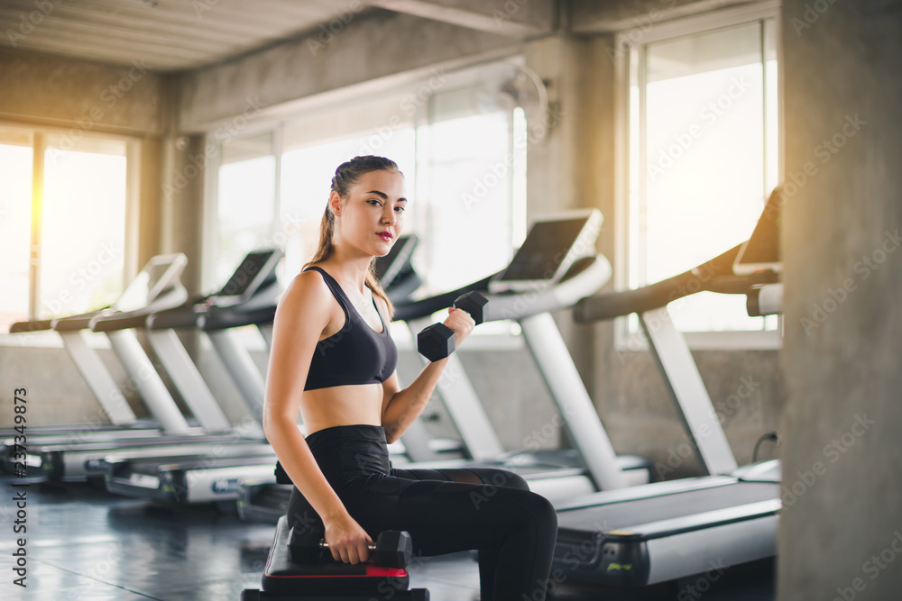 Beautiful girl caucasian is exercising with lifting dumbbell in the gym. Female athletes play a healthy training session. Beautiful girl caucasian is exercising with lifting dumbbell in the gym. Female athletes play a healthy training session.