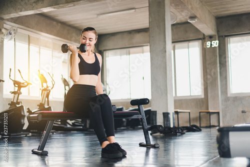 Beautiful girl caucasian is exercising with lifting dumbbell in the gym. Female athletes play a healthy training session.