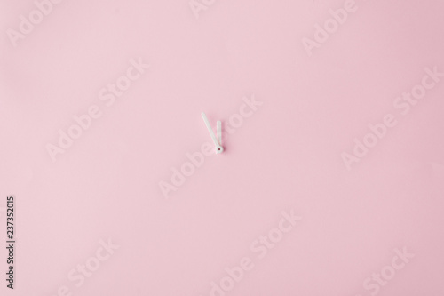 Clock hands on pastel pink painted wall. Minimal time concept.
