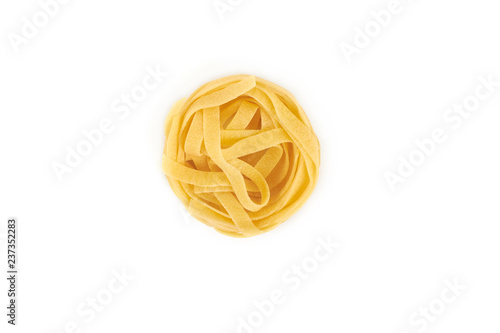 Uncooked nest of tagliatelle pasta isolated on white background.