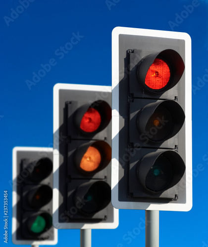 ROW OF THREE ROAD TRAFFIC LIGHTS SHOWING RED AMBER GREEN SEQUENCE WITH BLUE SKY