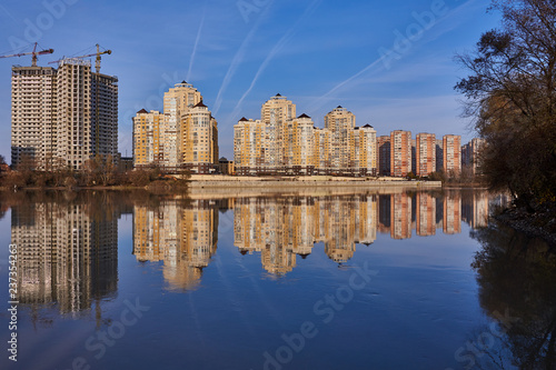 Chic View of the west of Krasnodar from the Kuban River in the winter in the golden hours. New high-rise buildings and clear blue skies are reflected in the water.