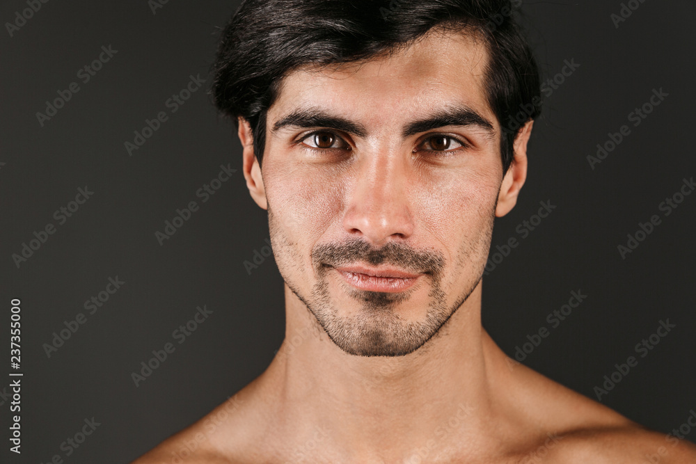 Naked young smiling man posing isolated over dark wall background. Naked young smiling man posing isolated over dark wall background.