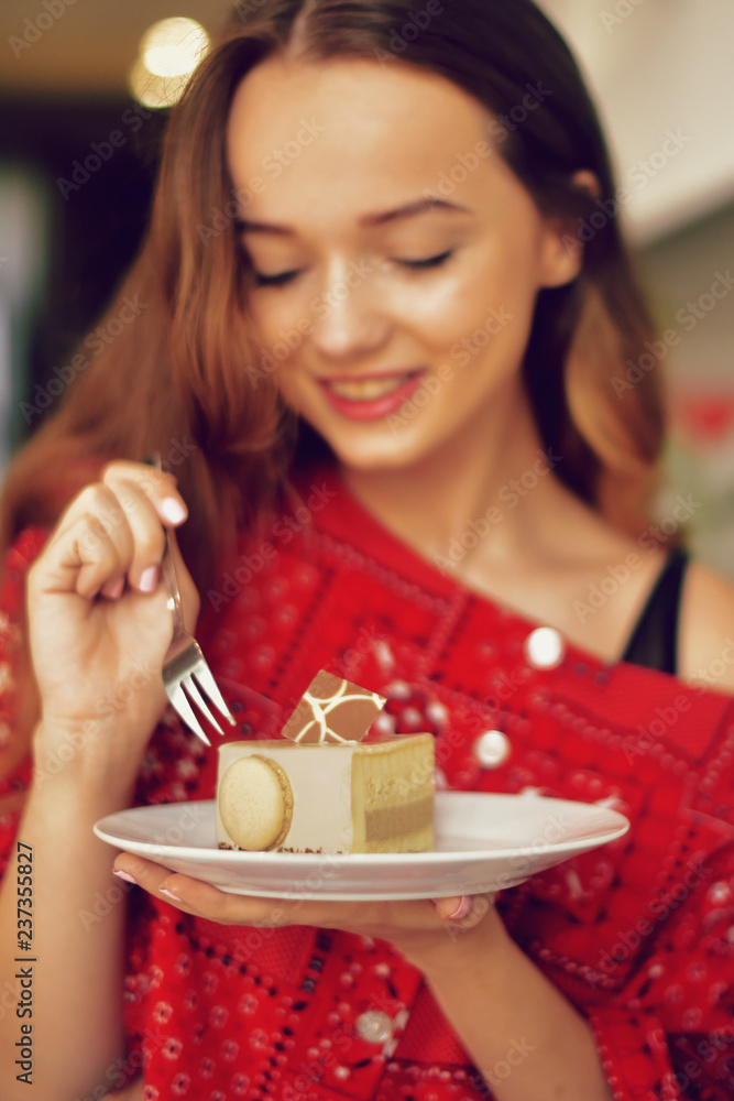 The girl in the bakery eats dessert. Beautiful model in a cafe eats sweets and smiling. Beautiful girl in a red sweater with long hair eats in a restaurant alone, diet. The girl in the bakery eats dessert. Beautiful model in a cafe eats sweets and smiling. Beautiful girl in a red sweater with long hair eats in a restaurant alone, diet.