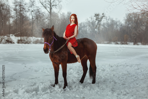 Beautiful woman in a red dress and pointe sitting on horseback.