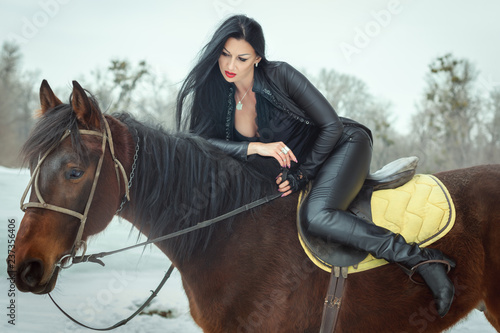 Brunette woman sits on horseback. © Petro