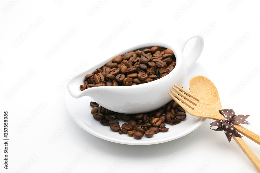 Fototapeta premium Coffee beans in a ceramic milk jug with fork and spoon