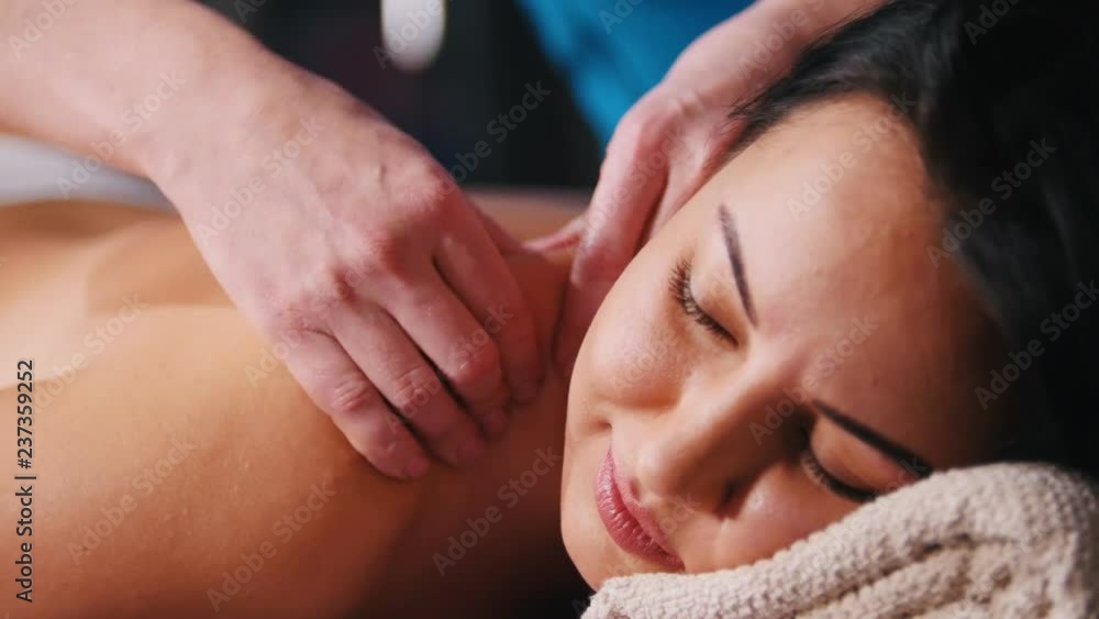 Massage treatment. A smiling client lays on the couch and receiving the massage. Close up Massage treatment. A smiling client lays on the couch and receiving the massage. Close up
