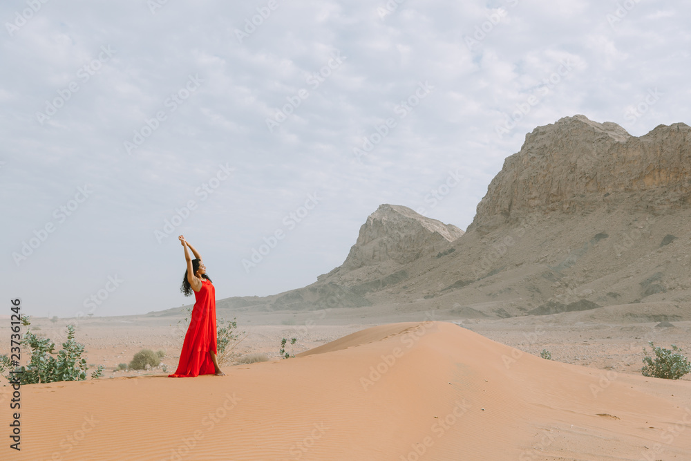 Young beautiful indian woman in red dress standing in the desert with ...
