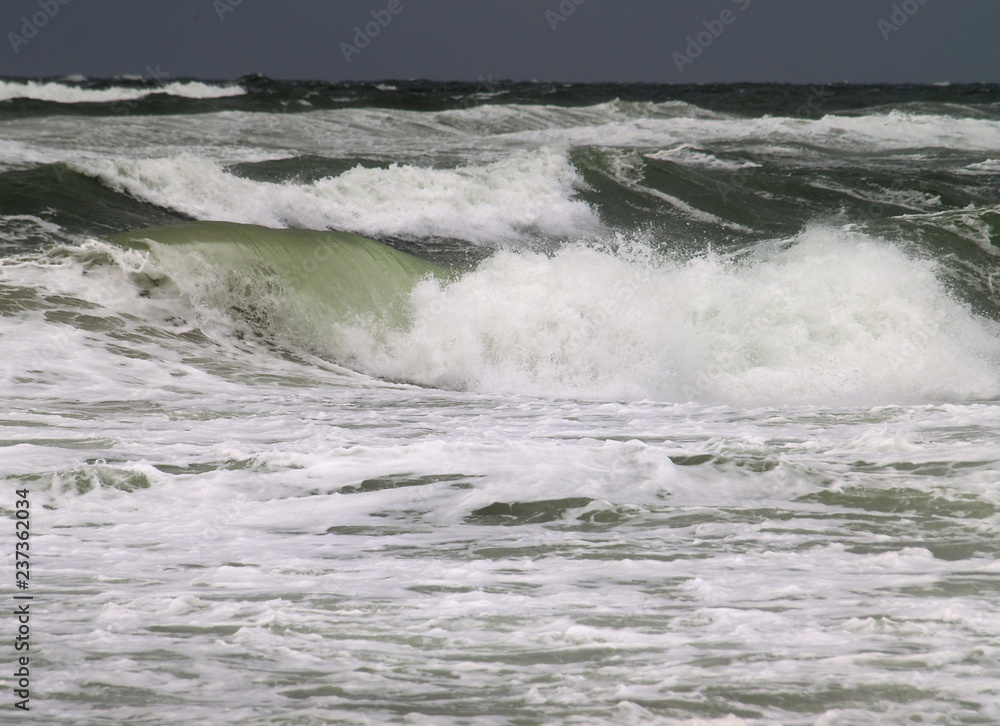 Fototapeta premium große Wellen am Strand von Kampen/Sylt, vor einem dunklen Himmel