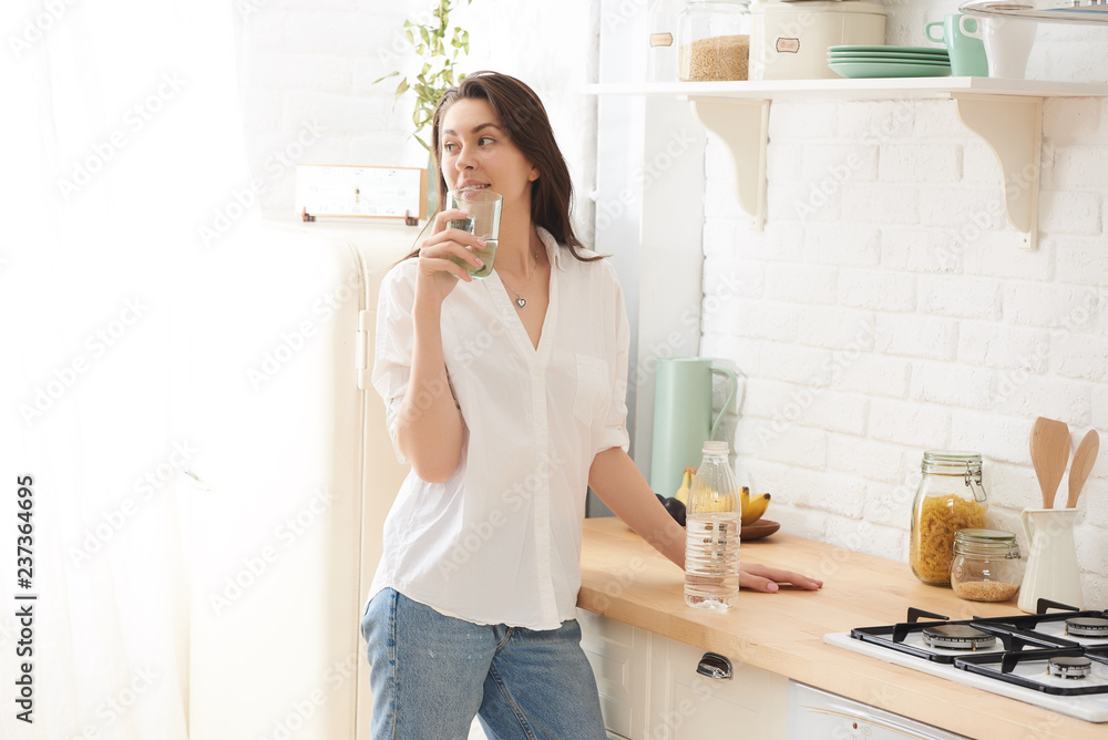 Young happy woman drinking coffee on the kitchen in the morning. Young happy woman drinking coffee on the kitchen in the morning.