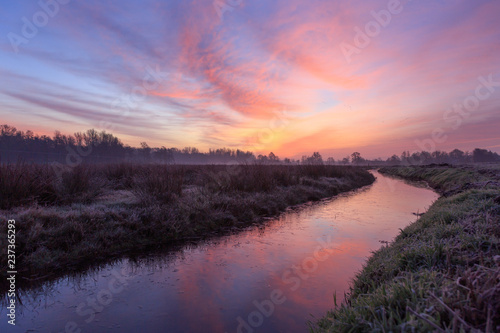Tranquil  pink dawn at a ditch in the Dutch countryside. Groningen  Holland.