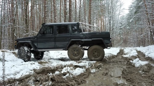 SUV 6x6 overcomes off-road in the winter forest. Jeeping
