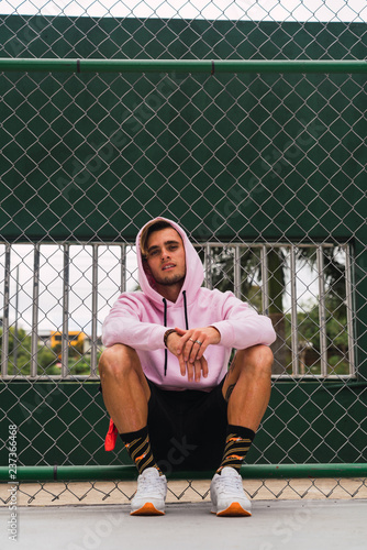 Yong man sitting near sports ground fence photo