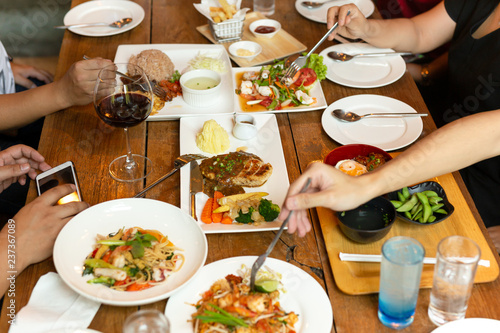 Group of friends hands with fork having fun eating variety food on the table.