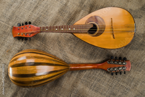 Two old mandolins on a background of rough burlap texture. View from different sides.