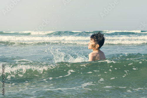 Boy Jumping In Sea Waves with Water Splashes. Concept of summer vacation © flowertiare