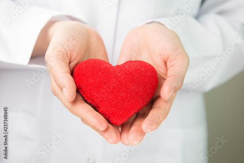 Female doctors s hands holding red heart and putting stethoscope s head close to it. Medical help or insurance concept. Cardiology care and health. Heart surgery and resuscitation concept 