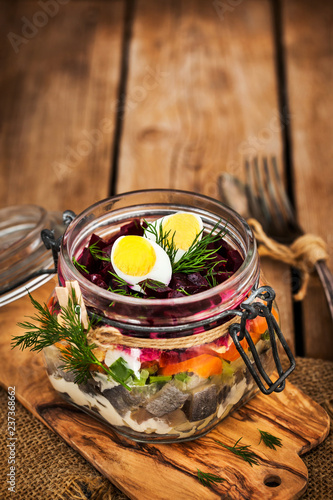 Traditional Russian layered betroot and herring salad (under a fur coat) in glass jar photo