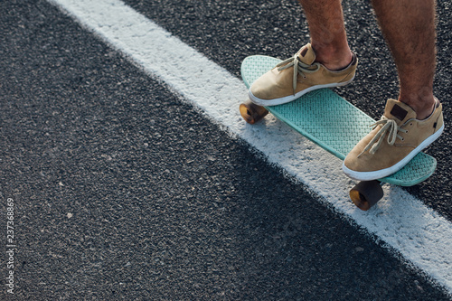 Close up of a skateboarders feet while skating on asphalt city road.