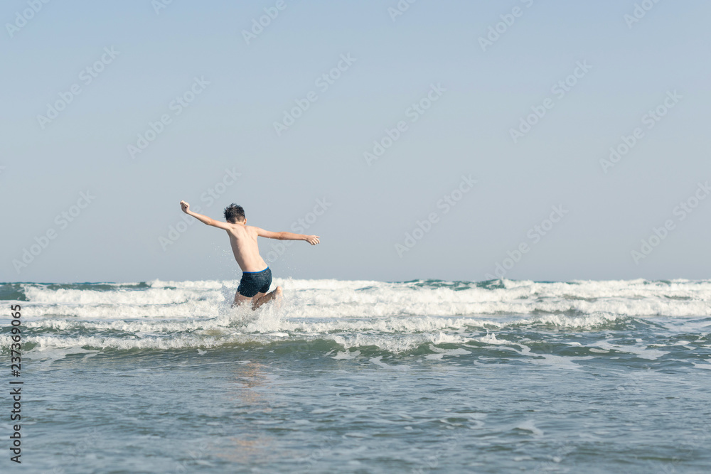 Boy Jumping In Sea Waves with Water Splashes. Concept of summer vacation