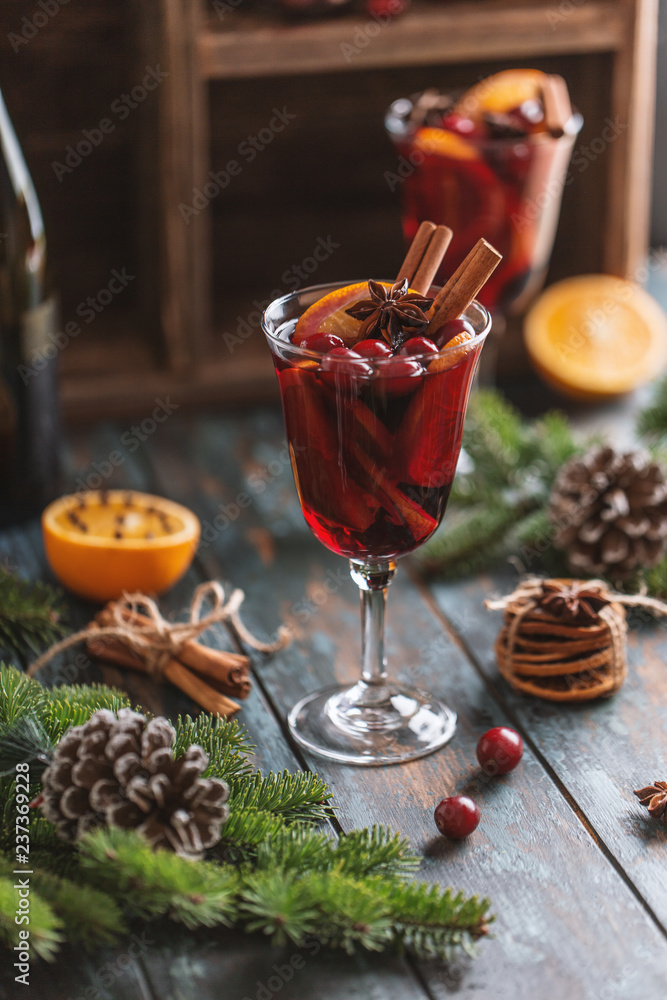 Christmas hot mulled wine in a glass with spices, citrus fruit and cranberry. Christmas atmosphere. 