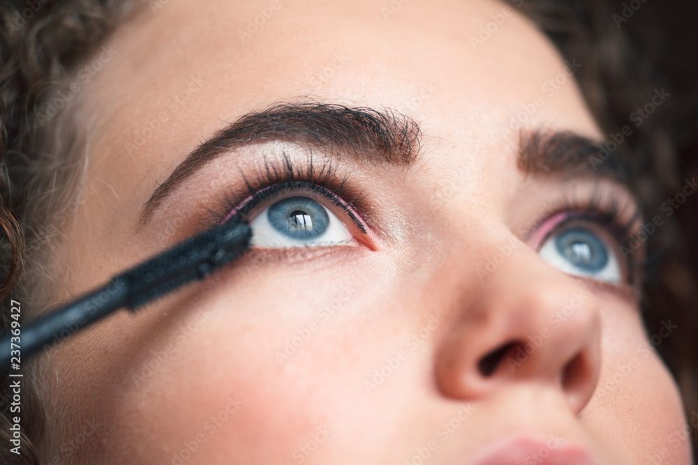 Closeup of makeup artist applying smokey eyes makeup. Eyelash extension procedure.