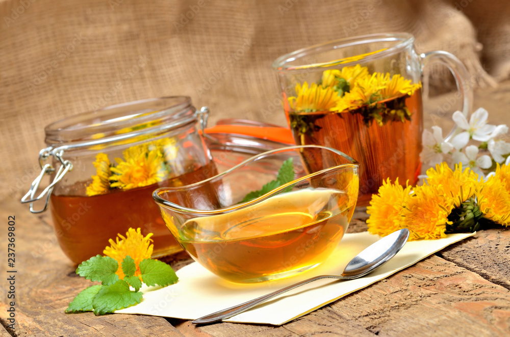 Dandelion honey, herbal tea, full jar of honey, spring flower, fresh mint leaves, spoon and dandelion head around - healthy snack Dandelion honey, herbal tea, full jar of honey, spring flower, fresh mint leaves, spoon and dandelion head around - healthy snack