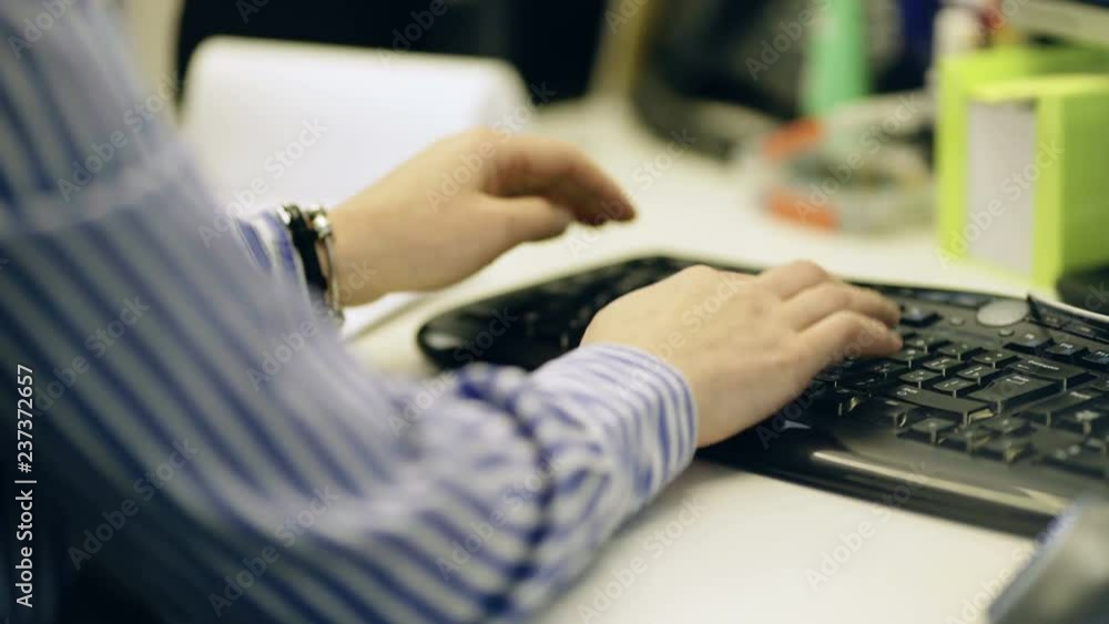 A man in a striped shirt in the office. Man typing on keyboard. Closeup view A man in a striped shirt in the office. Man typing on keyboard. Closeup view