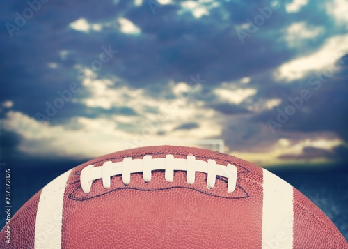 American football ball on stadium field background