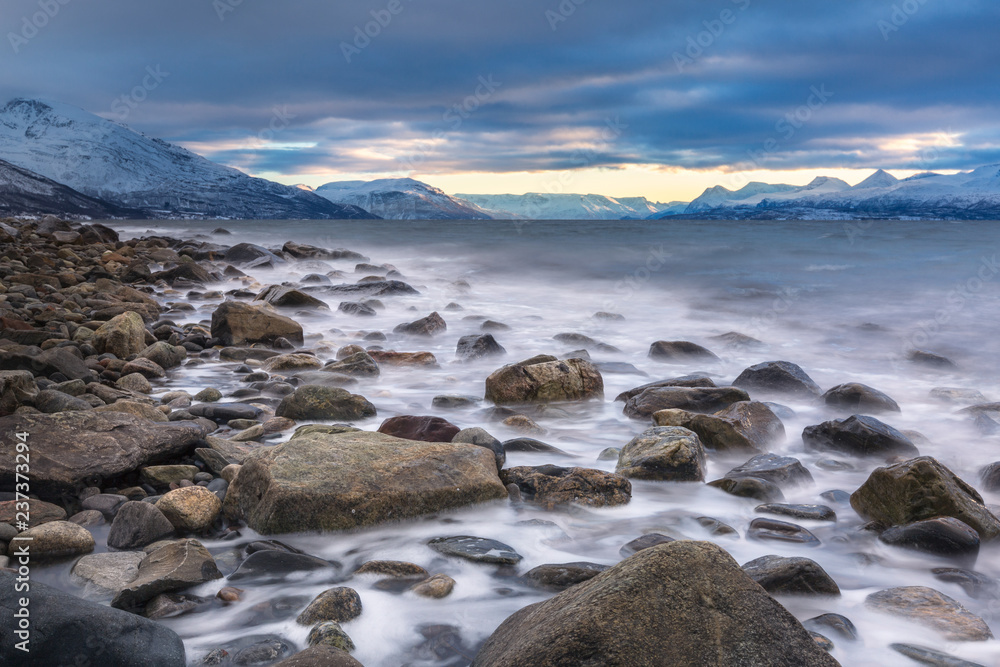 Beautiful stony seashore with blurred water and mountains on background Beautiful stony seashore with blurred water and mountains on background