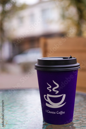 Purple coffee paper cup on glass clear table. On cup wrote: 