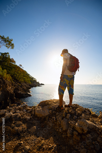 Traveler stands on the rock and admires turquoise waters