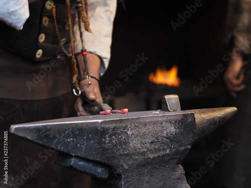 Blacksmith working metal with hammer in the forge for good luck on a christmas market in Cologne.