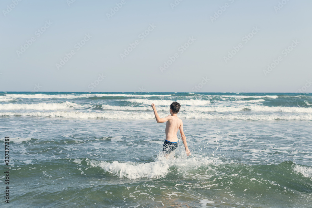 Fototapeta premium Boy Jumping In Sea Waves with Water Splashes. Concept of summer vacation